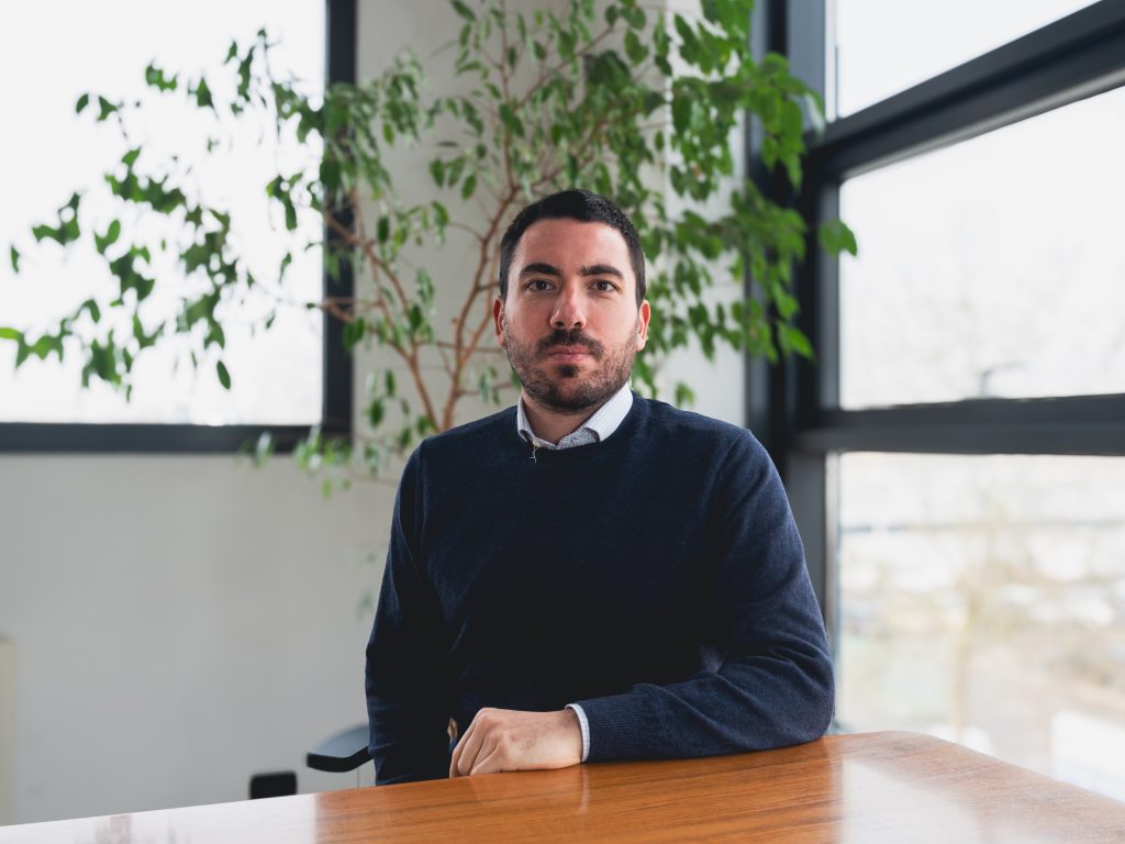 Isinet Consulting Uomo seduto in un ambiente moderno con piante, esprimendo professionalità e concentrazione.
