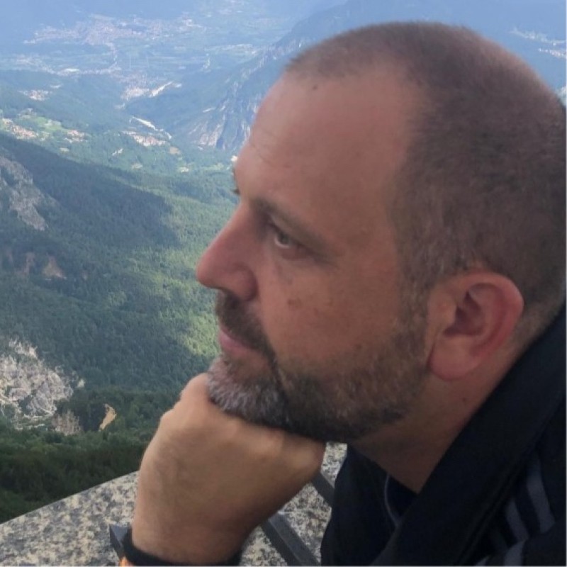 Isinet Consulting Uomo pensieroso che osserva un panorama montano verde.