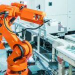 Isinet Consulting Braccio robotico industriale arancione in una fabbrica moderna, ideale per il Bando SI4.0 2026 Lombardia: guida al contributo fino a 30.000€.