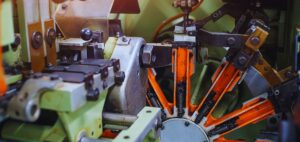 Isinet Consulting Dettaglio ravvicinato di un macchinario industriale con componenti meccaniche arancioni e metalliche, ideale per Bando Metalmeccanica 2026 Veneto.