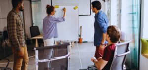 Isinet Consulting Un team di giovani professionisti collabora in ufficio davanti a una lavagna, valutando il Fondo Starter Emilia Romagna: mutuo a tasso zero per nuove imprese.